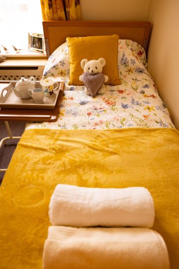 Bed with folded towels and teddy