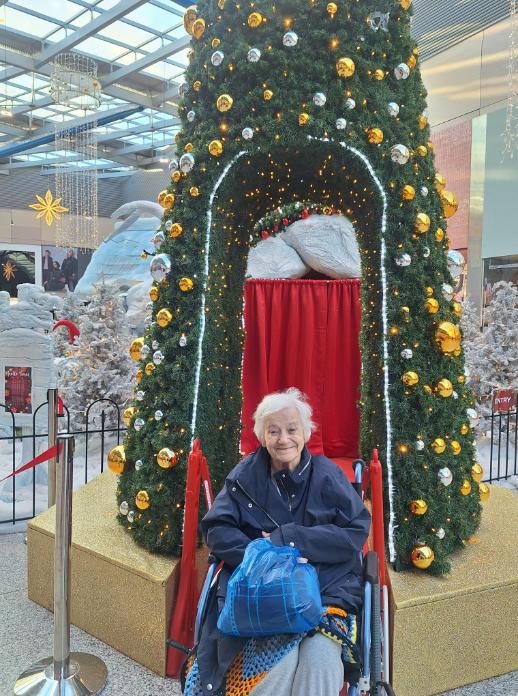 resident in a wheelchair smiling in front of a christmas tree