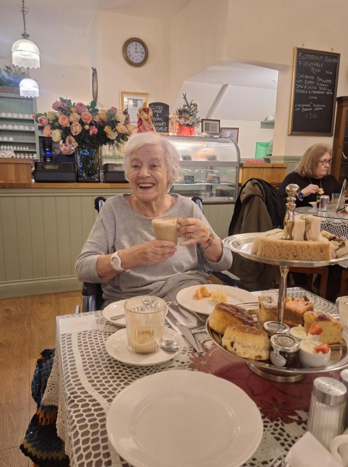 resident smiling enjoying tea and cake on a day out